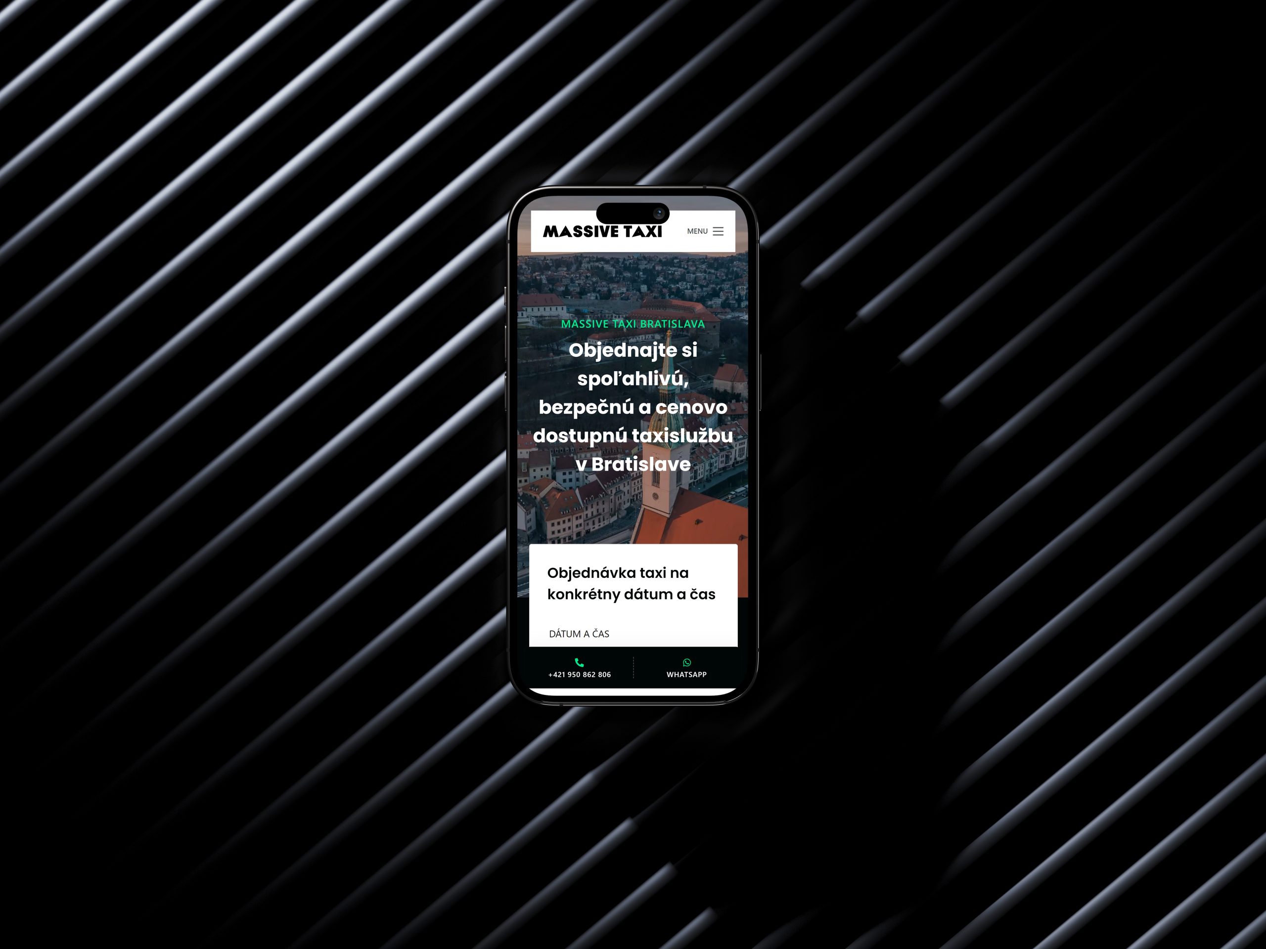Záber na iPhone 14 pro položený na šedom plechovom podklade s diagonálnou textúrou. Na displeji je zobrazená hlavná stránka webu Massive Taxi